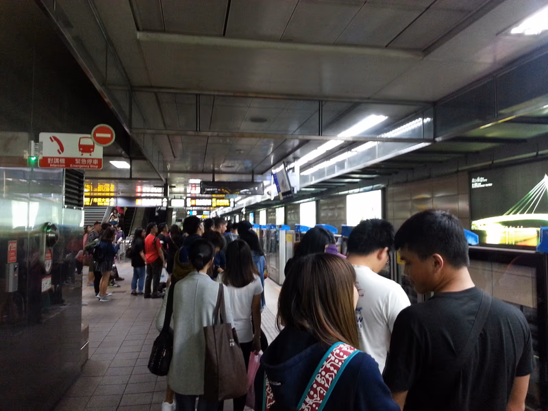 A busy train station with people waiting for their train and signage indicating directions and information.